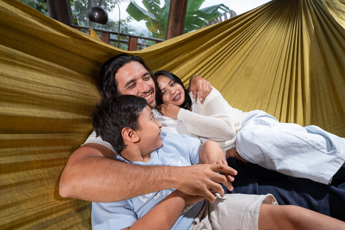 Vater, Mutter und Sohn kuscheln und lachen gemeinsam in einer goldenen Home Hammock 520