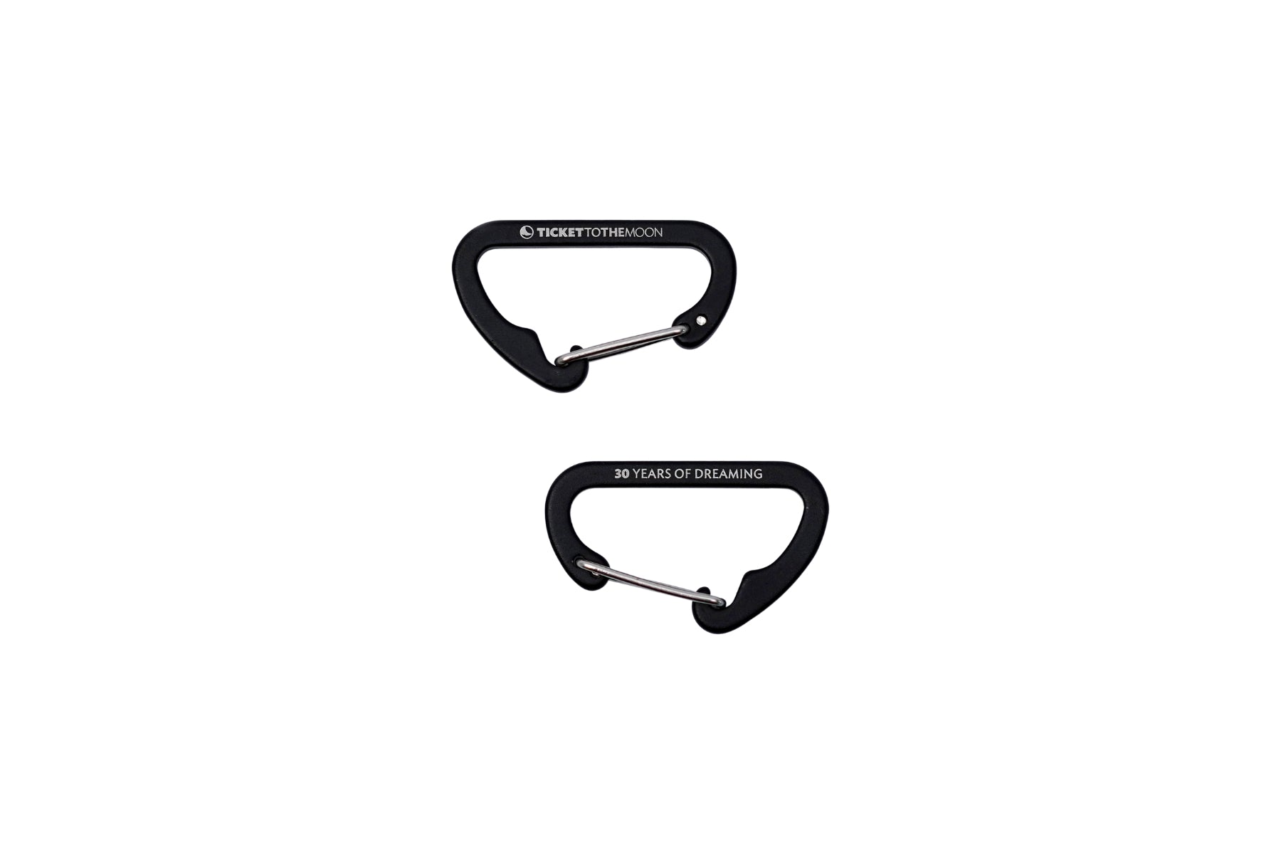 Zwei schwarze Mini-Karabiner von Ticket to the Moon vor weißem Hintergrund. Ein Karabiner zeigt das Markenlogo, der andere die Jubiläumsgravur „30 YEARS OF DREAMING“.