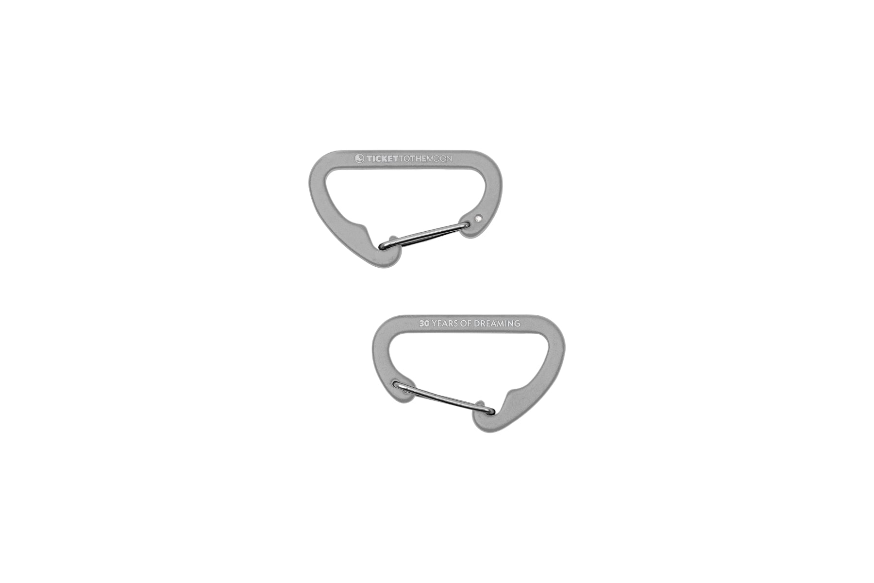Zwei weiße Mini-Karabiner von Ticket to the Moon vor weißem Hintergrund. Ein Karabiner zeigt das Markenlogo, der andere die Jubiläumsgravur „30 YEARS OF DREAMING“.