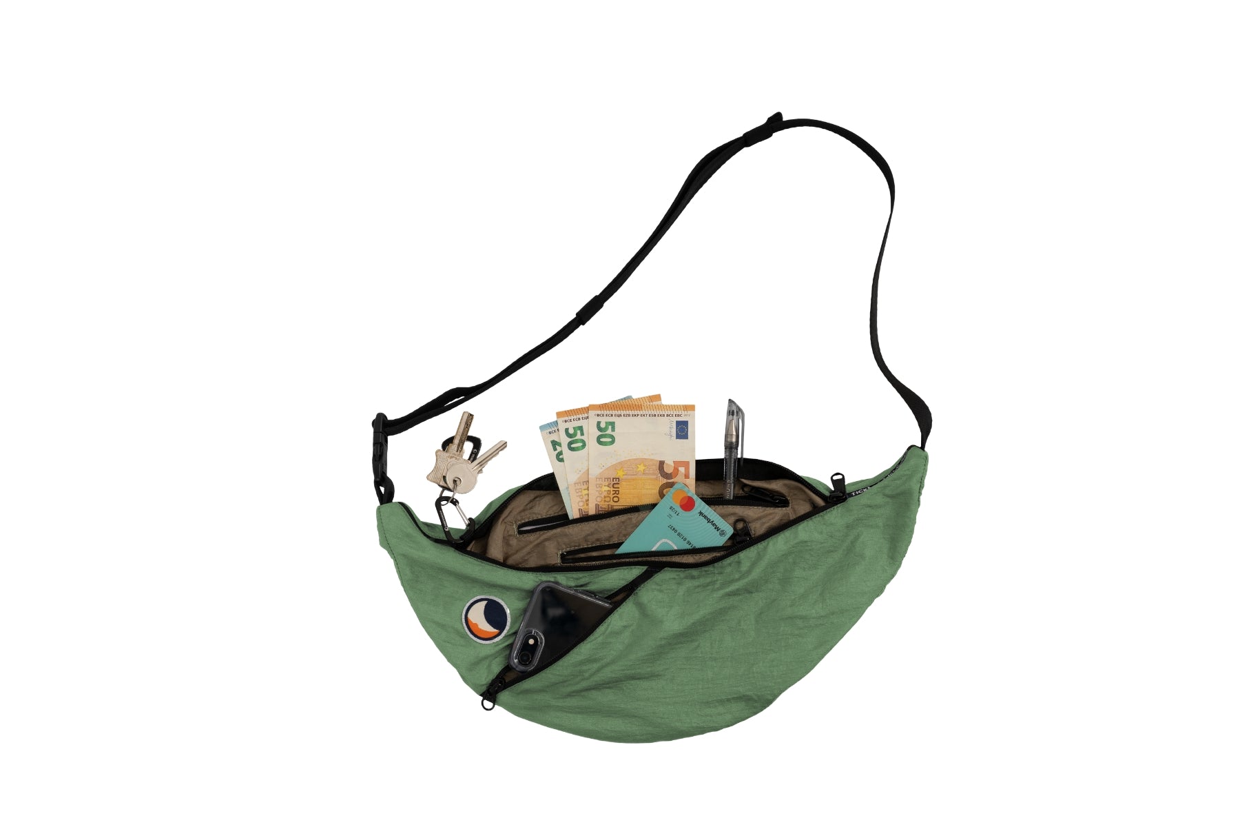 Geöffnete, hellgrüne (Jade Green) Sling Bag von Ticket to the Moon vor weißem Hintergrund. Die Tasche zeigt ihre Kapazität mit eingesteckten Essentials wie Bargeld, einer Karte, einem Smartphone, Schlüsseln und einem Stift.
