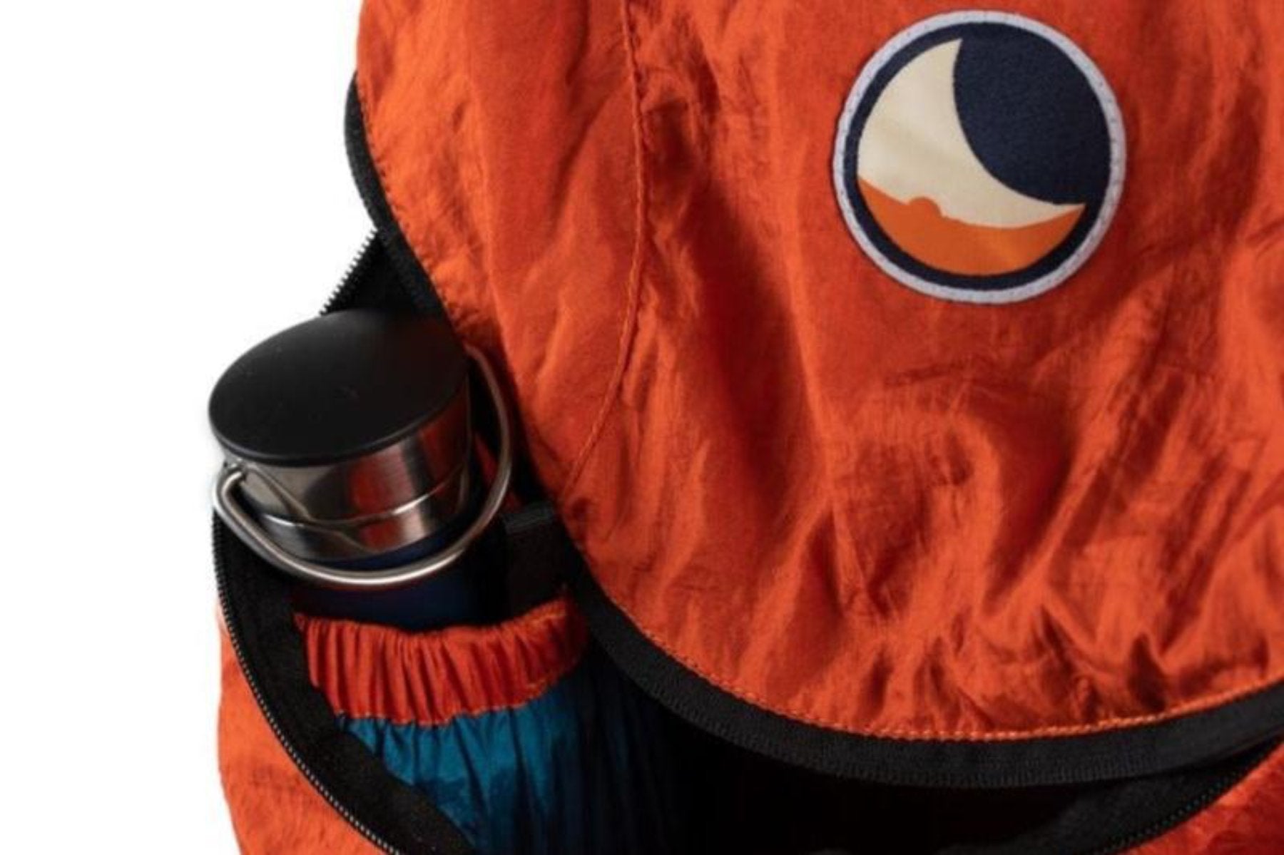 Detailaufnahme des orangefarbenen Backpack Plus von Ticket to the Moon mit geöffneter Reißverschlusstasche, in der eine Trinkflasche und ein verstautes Packteil sichtbar sind.