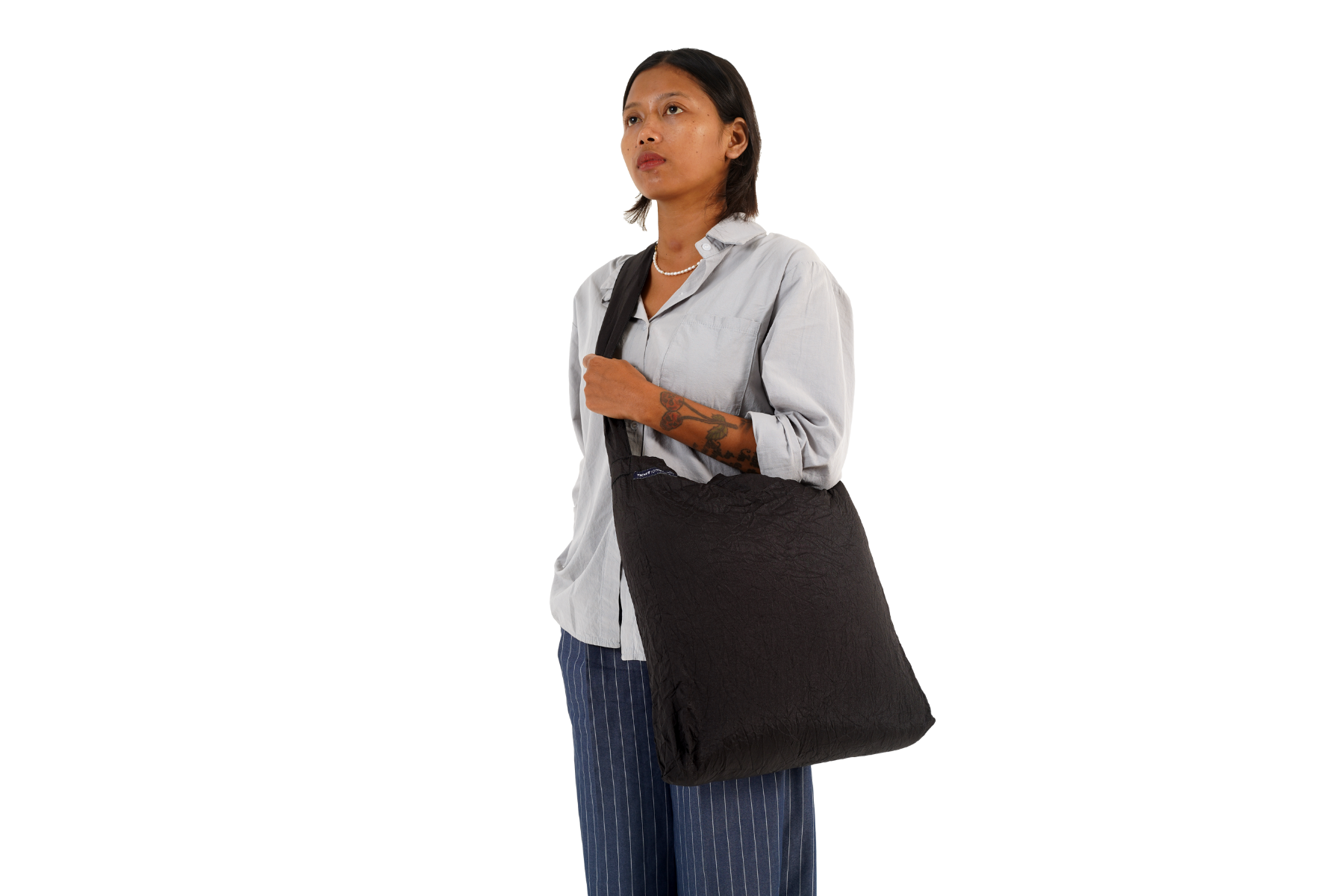 Frau mit schwarzer ECO BAG Large über der Schulter – nachhaltige Einkaufstasche aus Fallschirmnylon im minimalistischen Design.