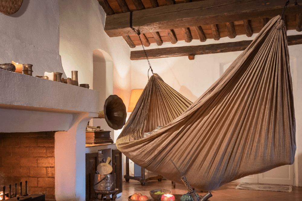 Große HOME HAMMOCK in warmer Umgebung mit Kamin und Holzbalkendecke, gemütlich aufgehängt im Wohnzimmer.