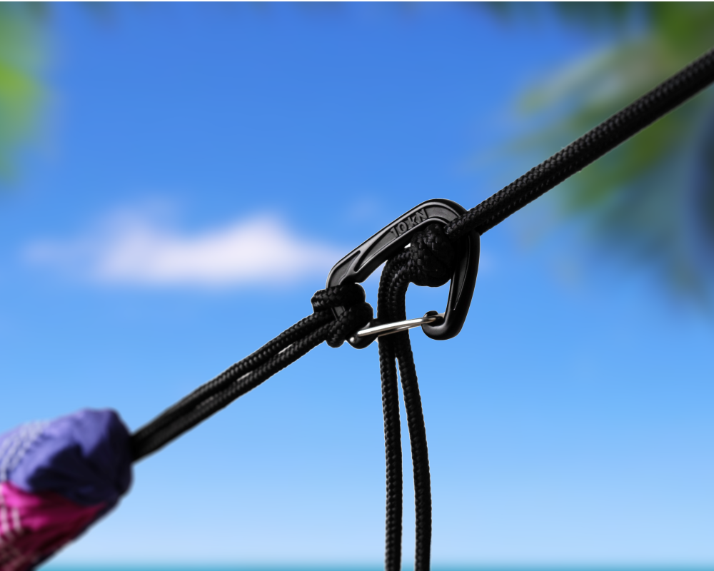 TTTM Karabiner sichert eine Hängematte mit schwarzem Seil am Strand – ideal für entspannte Outdoor-Abenteuer