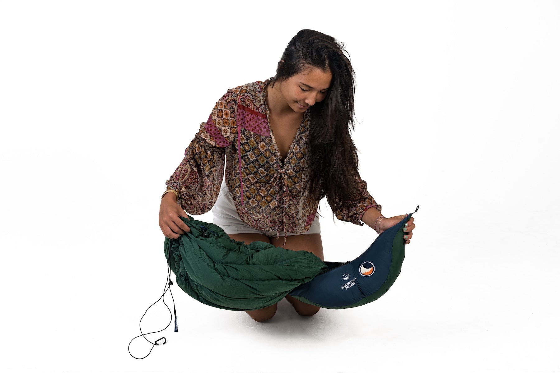 Frau präsentiert den MOONQUILT PRO 850 in kompakter Verpackung – ideal für unterwegs und Outdoor-Abenteuer.
