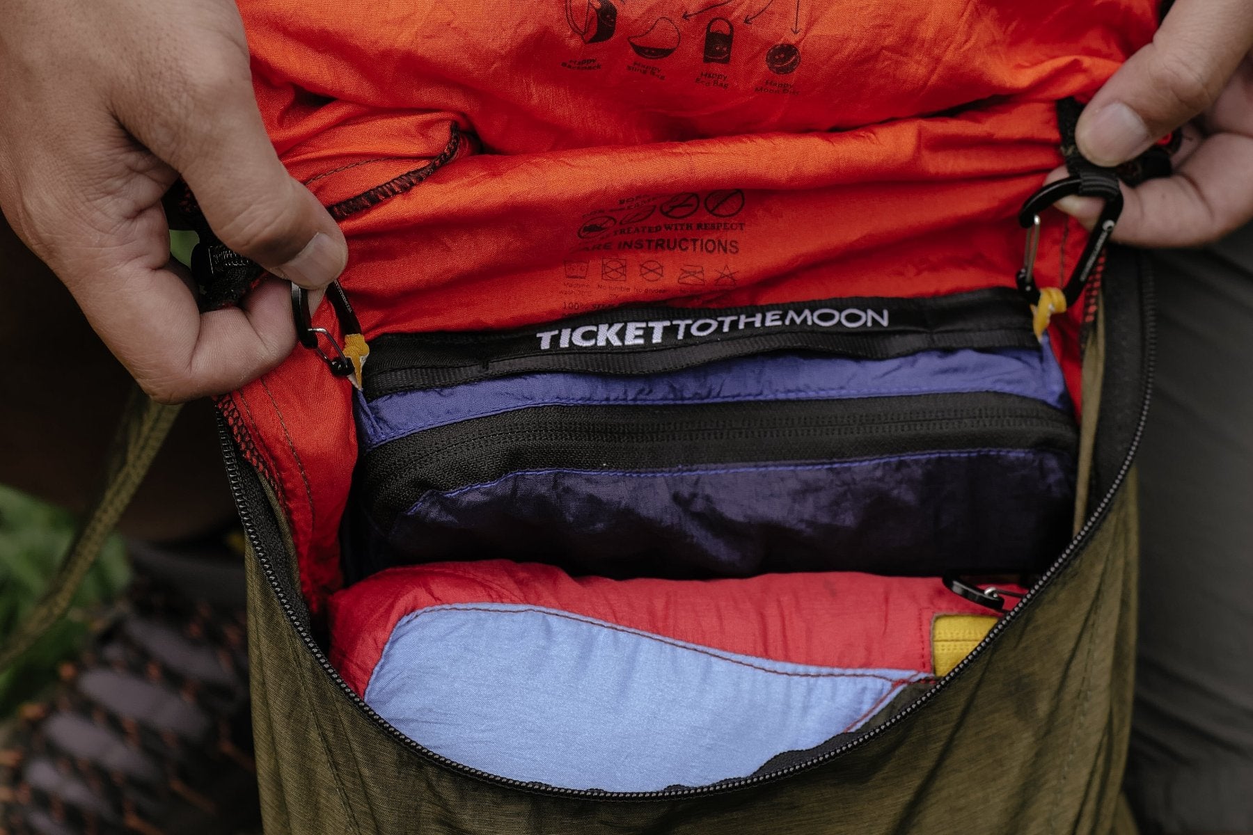 Ticket to the Moon Zubehörtasche sicher im Rucksackinneren befestigt, umgeben von farbenfroher Outdoor-Ausrüstung.