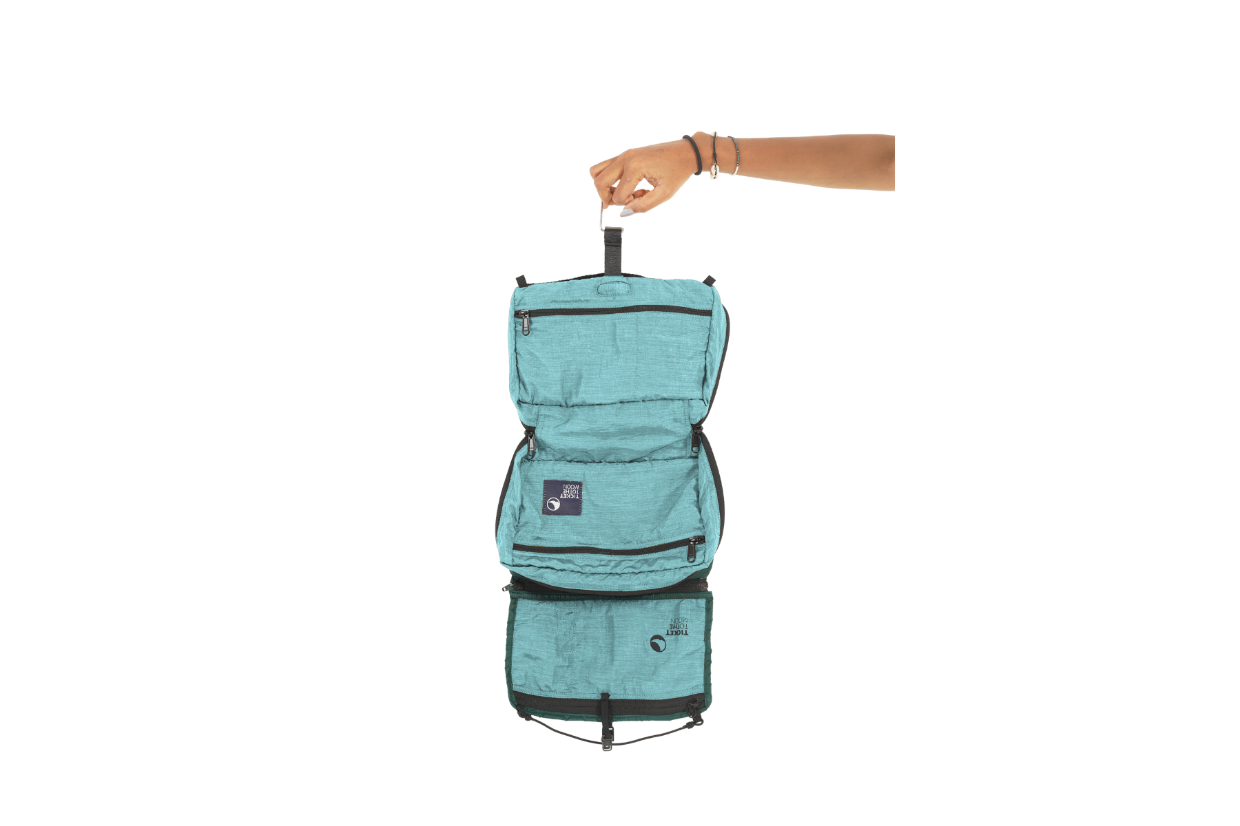 Komplett geöffnete Washbag von Ticket to the Moon in Türkis, an einer Hand gehalten – mit mehreren Reißverschlussfächern und praktischer Aufhängung für strukturierte Ordnung auf Reisen.