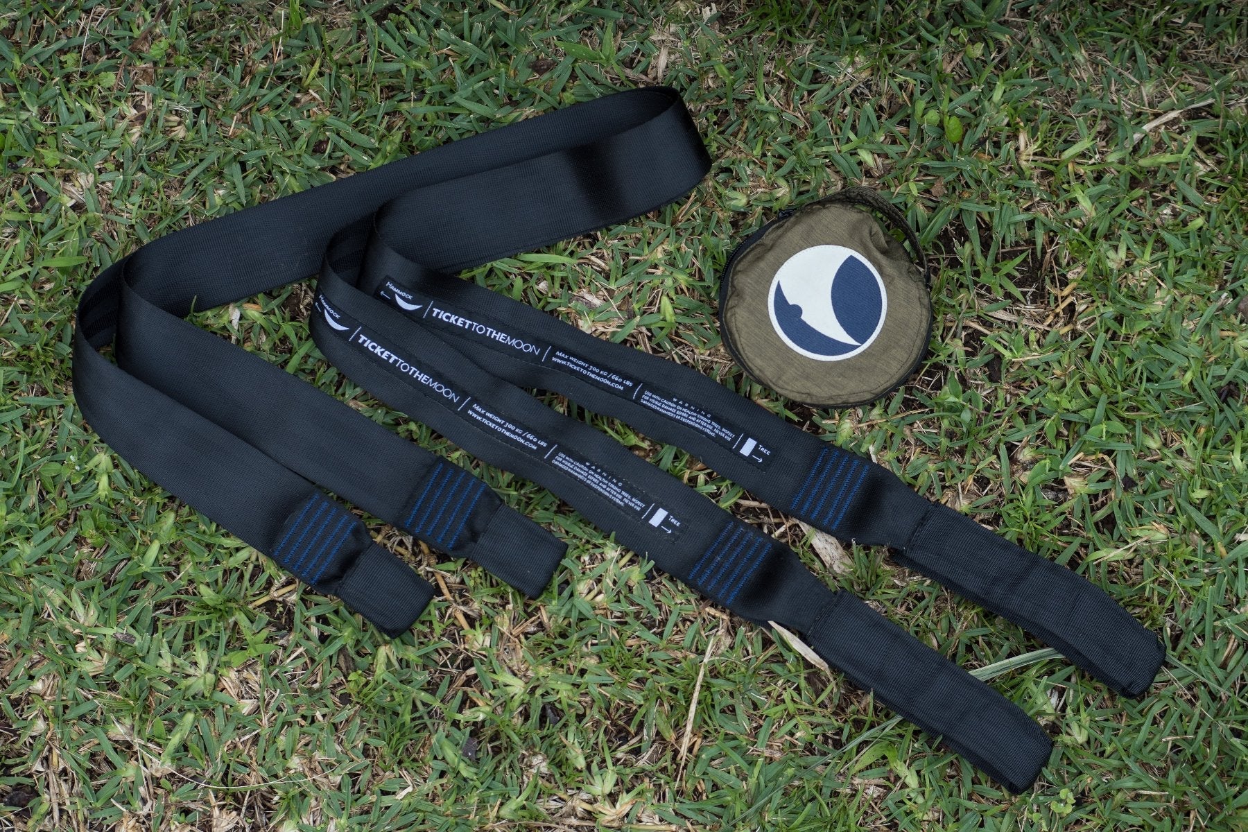 Ticket to the Moon Garden Straps aus schwarzem Gurtband mit verstärkten Schlaufen und Transportbeutel, ausgelegt auf einer Rasenfläche.