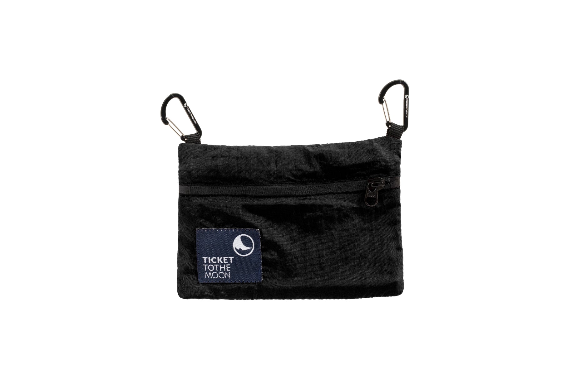 Eine kleine, rechteckige Ticket to the Moon Travel Pouch aus schwarzem Fallschirmstoff. Die Tasche zeigt ein schwarzes Logo-Patch, einen schwarzen Reißverschluss und zwei schwarze Mini-Karabiner an den oberen Ecken.