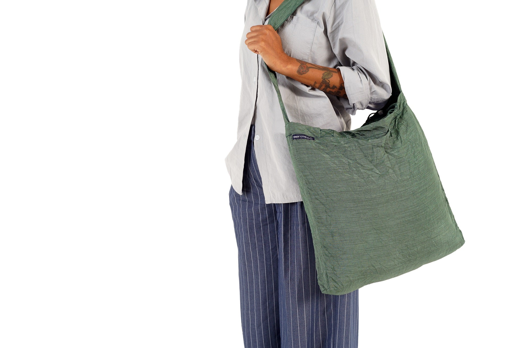 Person mit grüner ECO BAG Premium seitlich über der Schulter getragen.