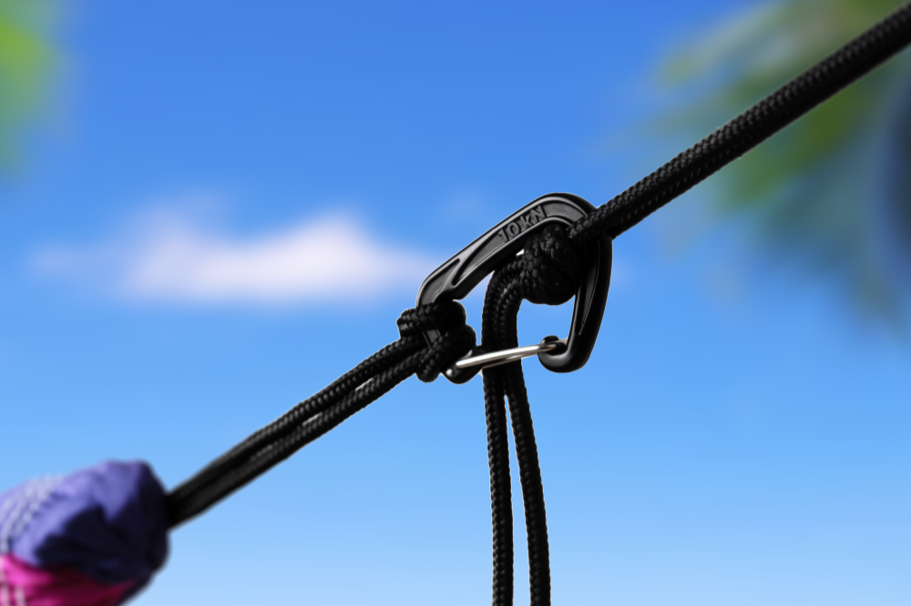 TTTM Karabiner sichert eine Hängematte mit schwarzem Seil am Strand – ideal für entspannte Outdoor-Abenteuer