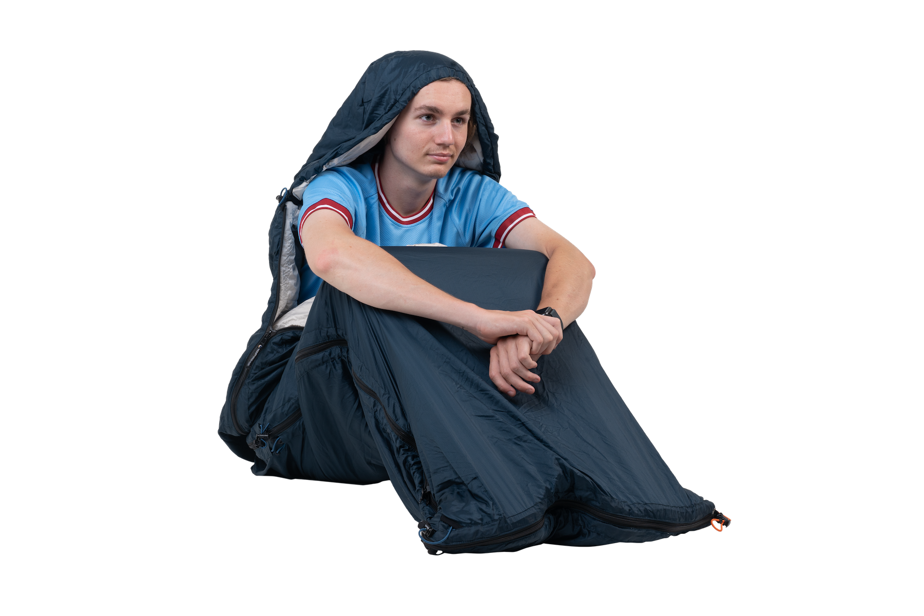 Person sitzt draußen und trägt den MOONQUILT wie eine wärmende Wickeldecke mit Kapuze – vielseitige Nutzung bei Kälte.