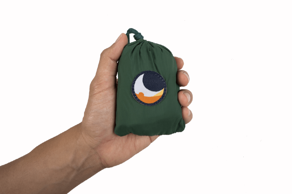 Kleine grüne Ridgeline-Verpackung mit Ticket to the Moon Logo wird von einer Hand gehalten, freigestellt vor weißem Hintergrund