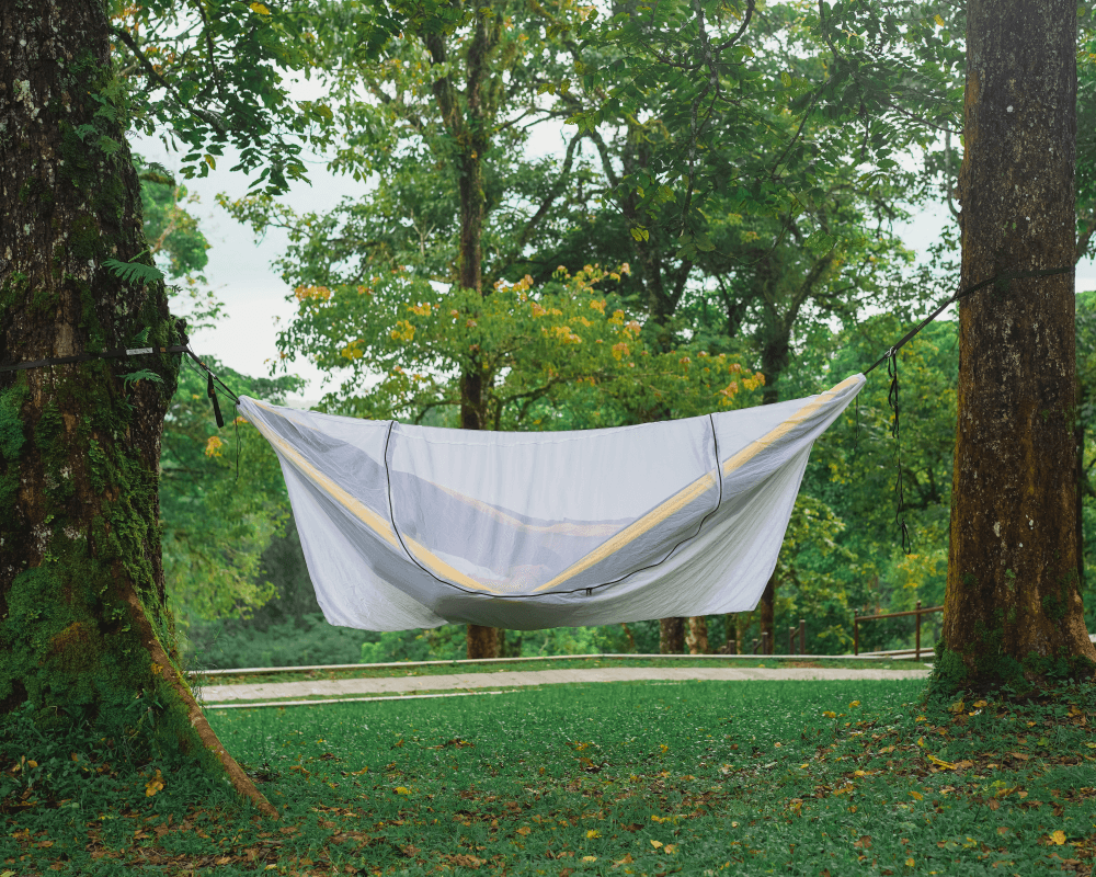 TTTM Hängematte mit weißem Moskitonetz zwischen zwei Bäumen – idealer Insektenschutz beim Camping im Wald