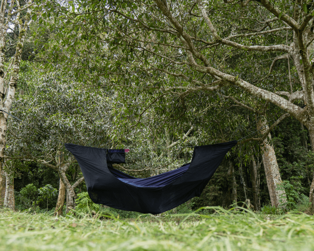 Schwarze TTTM Hängematte aufgehängt im dichten Wald – minimalistisches Setup für Naturverbundene und Bushcrafter