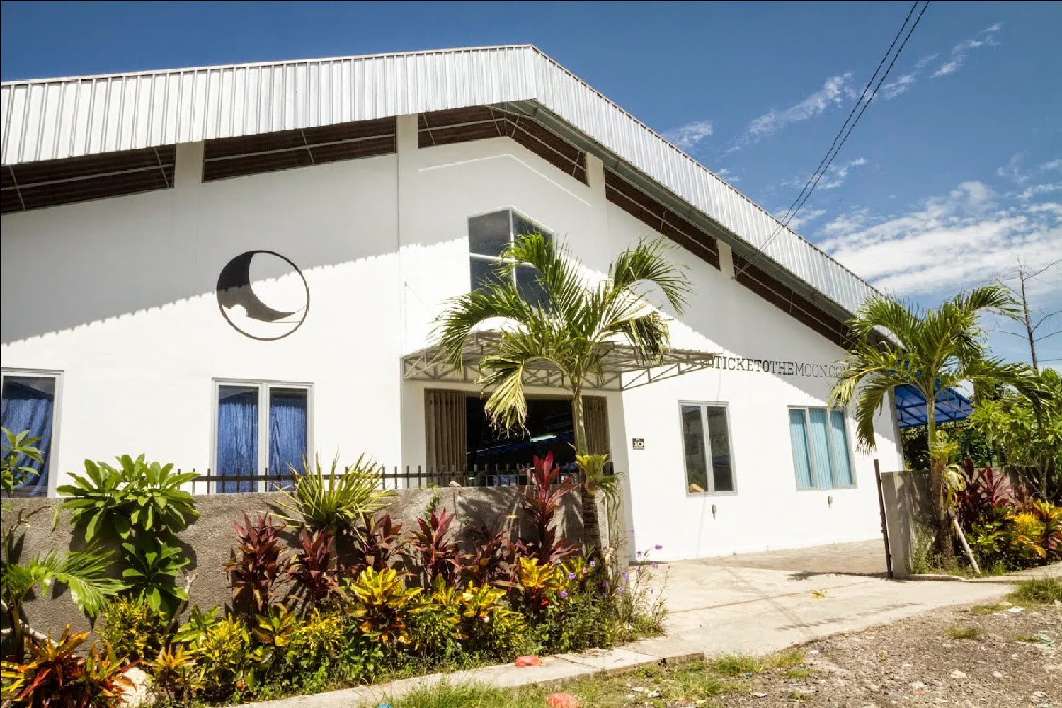 Außenansicht des TICKET TO THE MOON Headquarters in Bali mit tropischer Bepflanzung und blauem Himmel