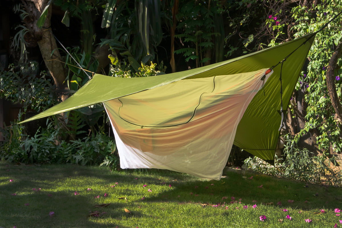 Hängematte mit UNIVERSAL BUG NET 360° unter einem grünen Tarp im Garten